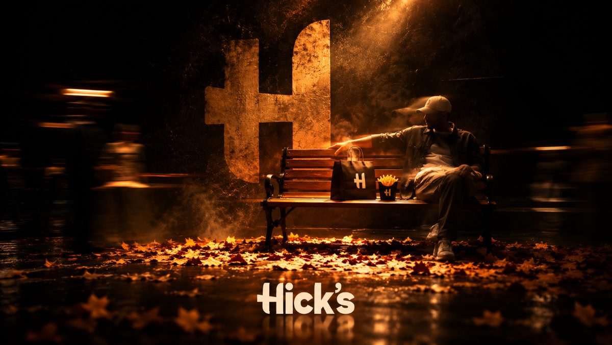 Banco iluminado com sacola e fritas do Hick’s, ao fundo o H da marca